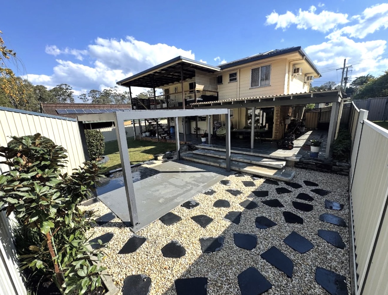 Elevated view of completed outdoor entertainment area, louvred pergola, concrete terrace, and stone pavers